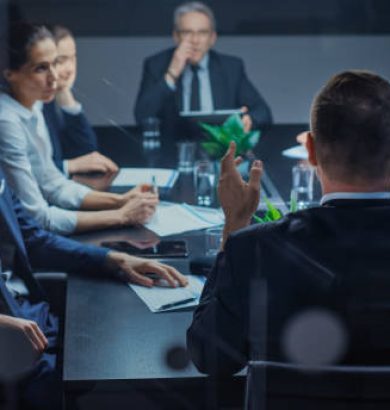 istockphoto-1224561371-612×612 Late at Night In the Corporate Office Meeting Room: At Conference Table Executive Director Talks to a Board of Directors, Investors and Business Associates. Over the Shoulder Shot.